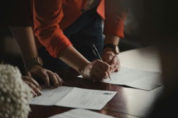 person-in-orange-long-sleeve-shirt-writing-on-white-paper.jpg person in orange long sleeve shirt writing on white paper